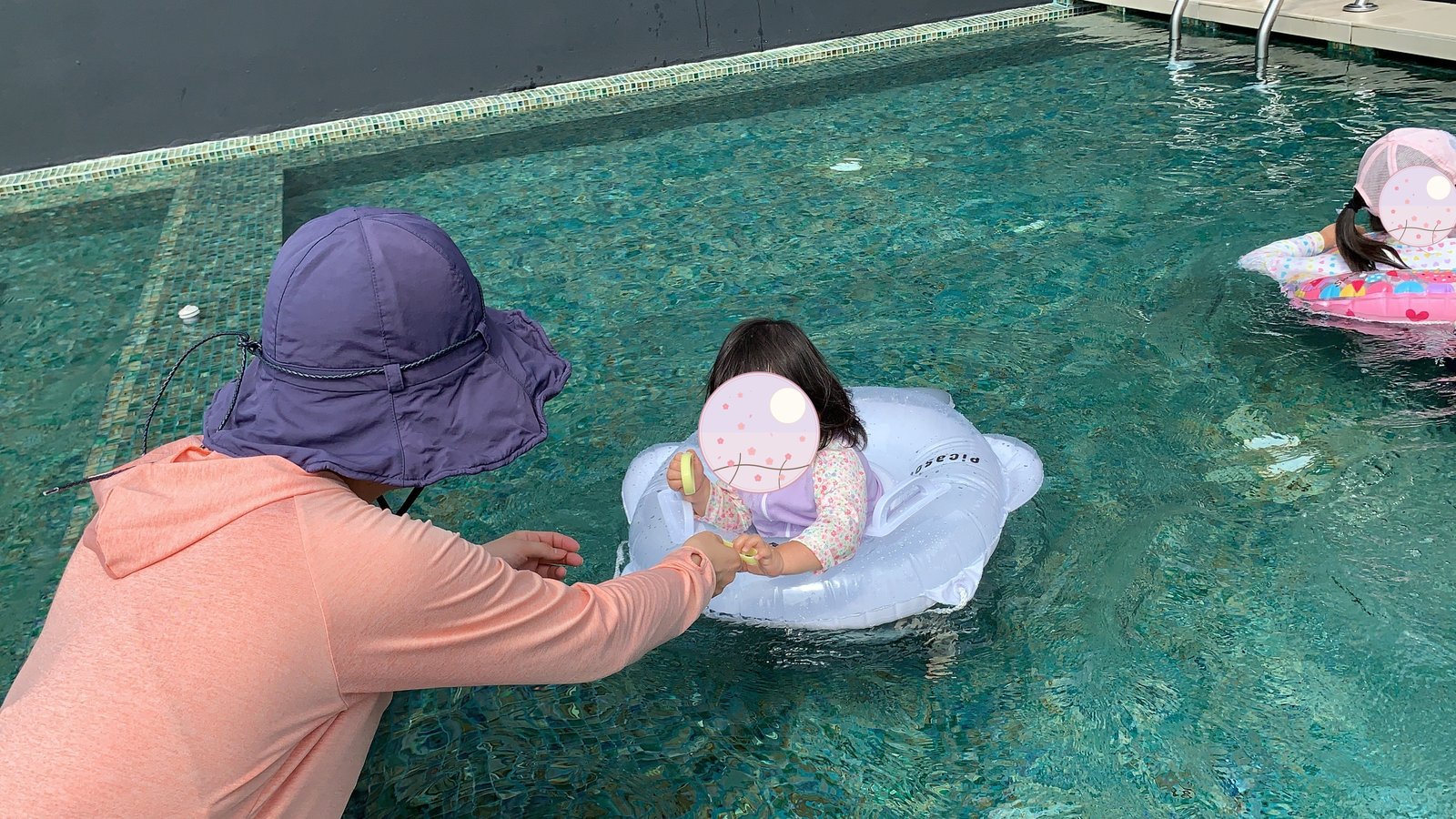 浮き輪をつけてプールに浮かぶ子どもに手を差し伸べる大人
