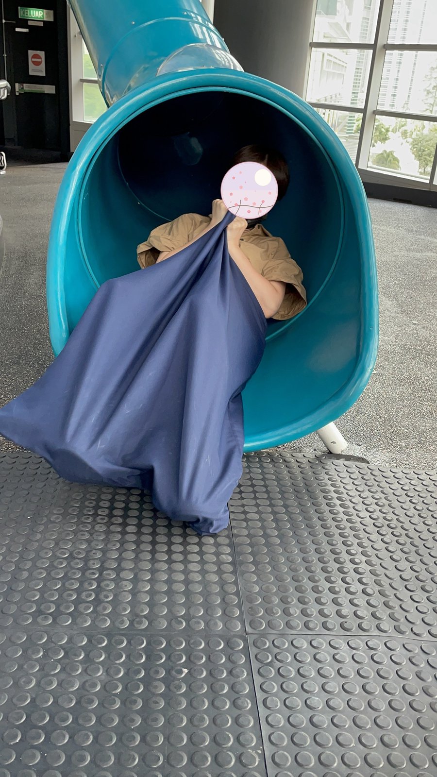 Wrapped in a blanket, sliding down the tunnel slide 